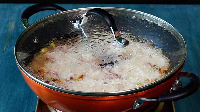 The orange non stick pan with rice is covered with a tight fitting and left on low heat for the water to be absorbed - Kerala Ghee Rice with California Walnuts Recipe